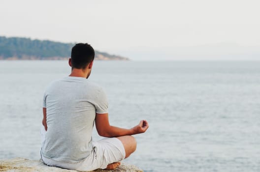Young man sitting on the coast and meditating