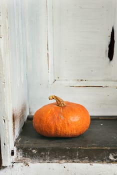 Orange pumpkin on the rustic wooden doorsetp.