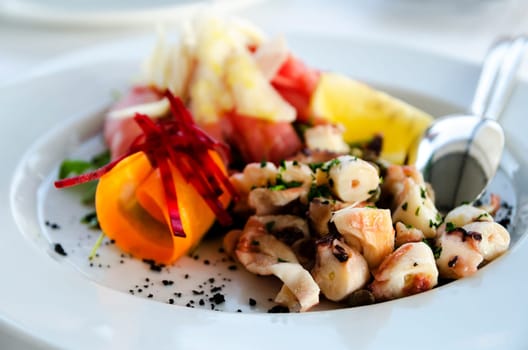 Mixed octopus salad in white plate. Shallow depth of filed.