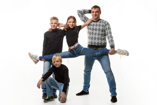 Dad and son hold their daughter on a stretch, the second son sits next to him, full-length portrait, white background