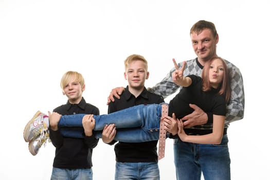 Dad and two sons hold a teenage girl in their arms, girl casual clothes in dark colors, white background