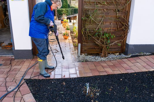 Worker cleaning driveway with gasoline high pressure washer splashing the dirt,professional cleaning services.High pressure cleaning,lower body.