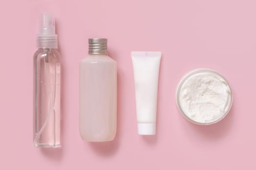 Homemade Cosmetics in plastic tubes and bottles on pink top view. Brand packaging mockup. Organic natural cosmetics for skin and hair care