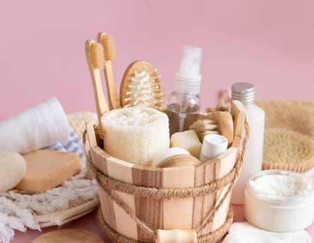 Sauna bucket with organic natural cosmetics and zero waste reusable accessories for skin and hair care on pink. Close up of eco friendly beauty products for bath, massage or spa salon