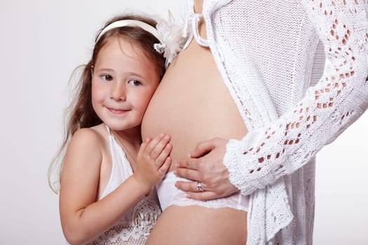 Daughter listening to her mother's pregnant tummy