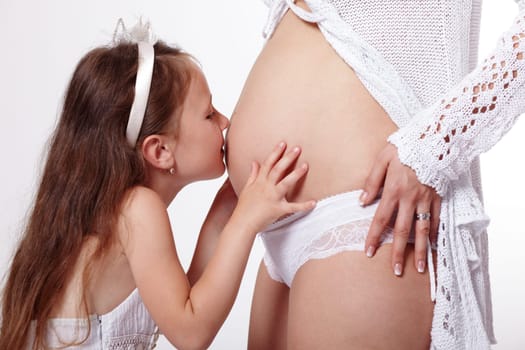 Daughter kissing her mother's pregnant tummy