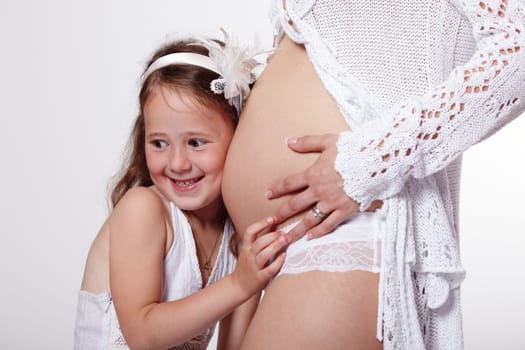 Daughter listening to her mother's pregnant tummy