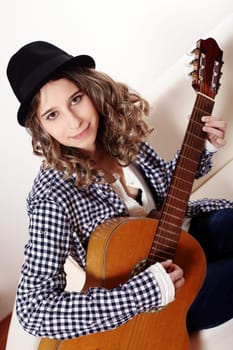 Young woman playing the guitar and sitting on a sofa