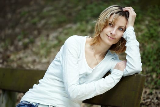 Portrait of smiling woman sitting on a bench in a park