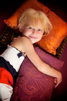 Portrait of a little girl lying among pillows