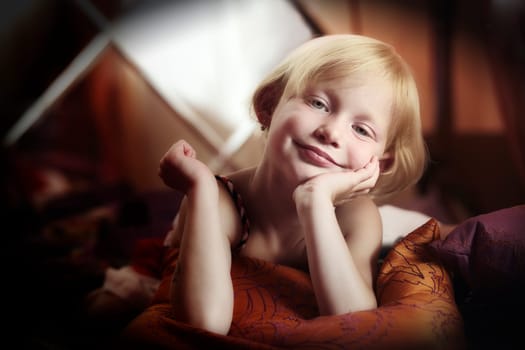 Portrait of a little girl lying on pillows