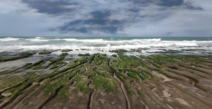 The Laomei Green Stone Trough is located in Shimen District on the North Coast, Every April and May, because the northeast monsoon slowly weakens, the local rock trough scientific name: tidal trench and sea erosion trench is covered with a large green seaweed