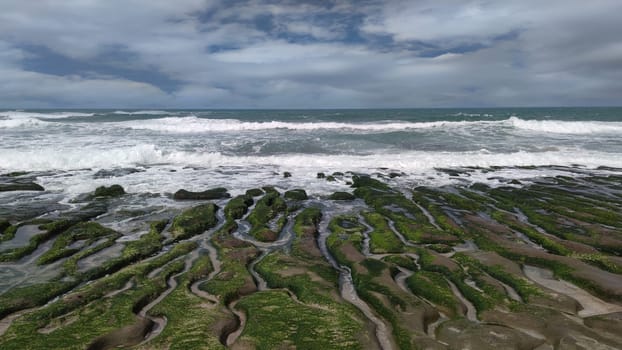The Laomei Green Stone Trough is located in Shimen District on the North Coast, Every April and May, because the northeast monsoon slowly weakens, the local rock trough scientific name: tidal trench and sea erosion trench is covered with a large green seaweed