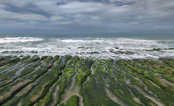 The Laomei Green Stone Trough is located in Shimen District on the North Coast, Every April and May, because the northeast monsoon slowly weakens, the local rock trough scientific name: tidal trench and sea erosion trench is covered with a large green seaweed