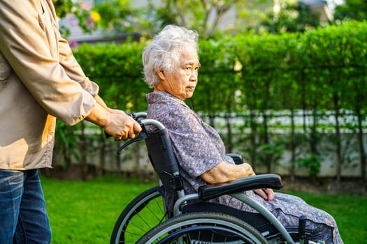 Asian elderly woman disability patient sitting on wheelchair in park, medical concept.