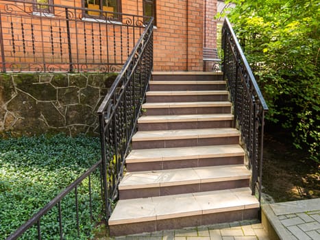 A beautiful staircase with metal railings rises to a red brick building