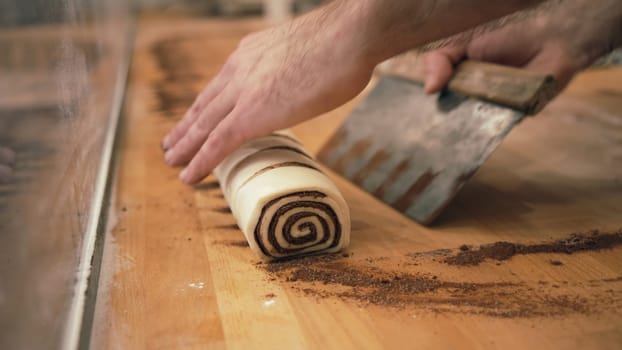 Baker working with handmade pastries in small bakery. Cocoa snail roll, chocolate roll. Closeup photo of not staged, authentic moment.