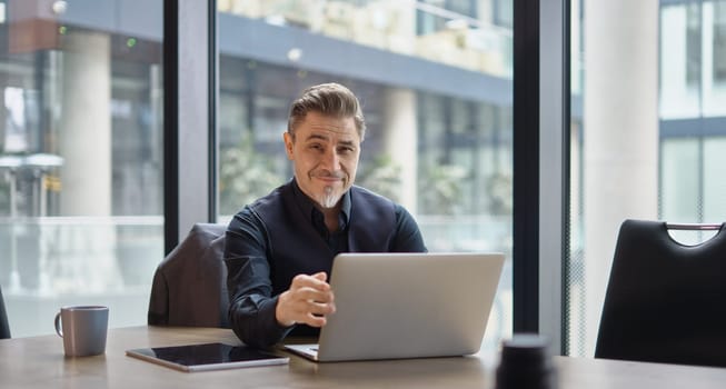 Businessman using laptop computer in office. Happy middle aged man, entrepreneur, small business owner working online.