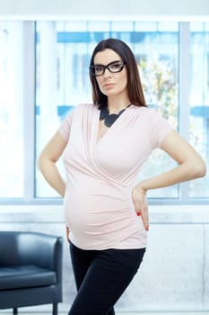 Today women working during pregnancy - Serious pregnant woman working in modern business office.