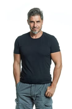 Portrait of happy sporty older white man standing against white background.