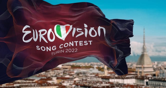 Turin, Italy, January 2022: The flag of the Eurovision Song Contest 2022 logo waving in the wind with blurred landscape of Turin city. The 2022 edition will take place in Italy from 10 to 14 May