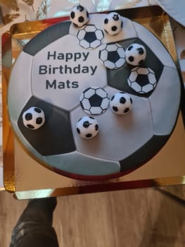 Funny and lovely sporty birthday cake. Design with the soccer field. Shoes, buildings, sports day. Cake, cream. green field. Birthday cake for a sports team.