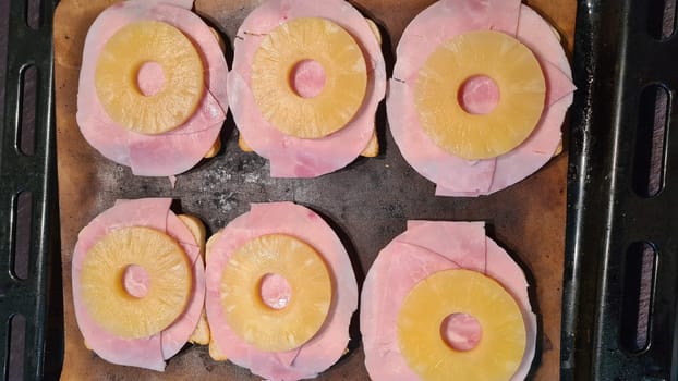 Hawaiian toast with ham, cheese and pineapple on a cutting board on a dark background, horizontal