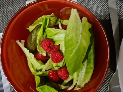 Fresh Tasty Raspberry salad with avocado, green vegetables, nuts, feta cheese, olive oil and herbs. healthy food.