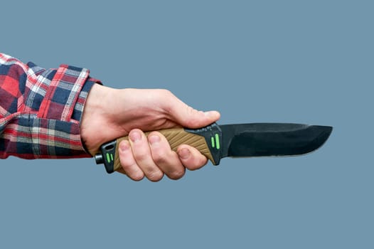 a man's hand holds a large tactical knife with a plastic handle on a gray background. High quality photo