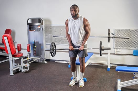 African-American man shakes biceps in the gym. High quality photo