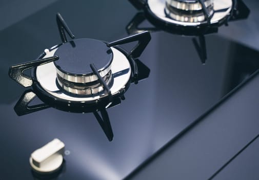 closeup perspective view of modern expensive black gas stove for camper RV with glass and metal finish on dials