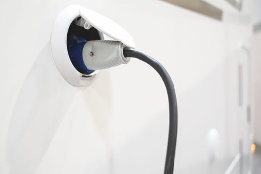 perspective view closeup of motorhome electricity outlet plug attached to stationary white RV travel campervan