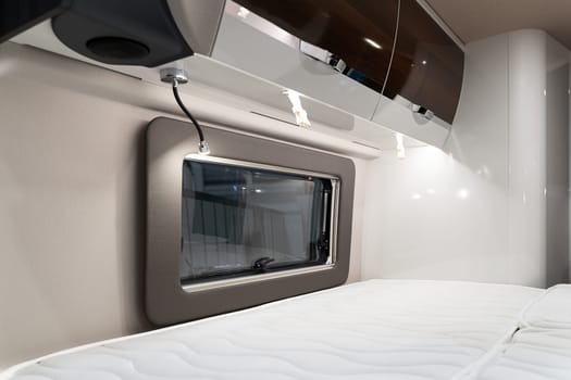 closeup of bed near window and storage shelves inside empty bedroom in luxury RV camper trailer interior