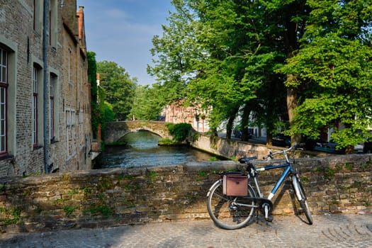 Typical Belgian scenic cityscape Europe tourism and bicycle transport concept - bicycle on a bridge near canal and old house. Bruges Brugge, Belgium