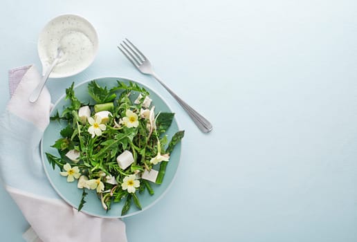 Spring salad with dandelion, asparagus, flowers, nettle and cream cheese. Healthy spring detox food ingredients.