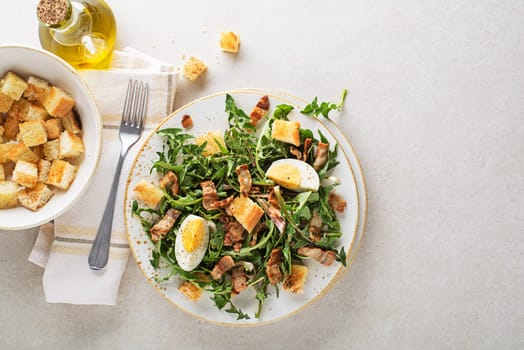 Dandelion salad with egg bacon and croutons on grey background