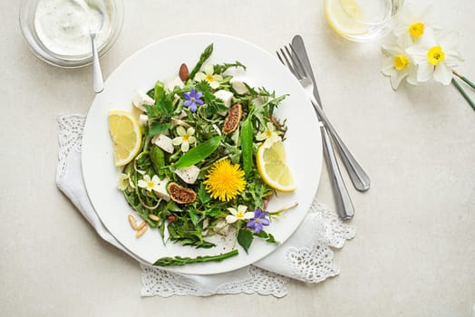 Spring salad with dandelion, asparagus, wild garlic, flowers, nettle and cream cheese. Healthy spring detox food ingredients.