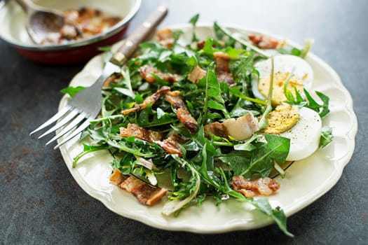 Dandelion salad with eggs and roasted bacon close up