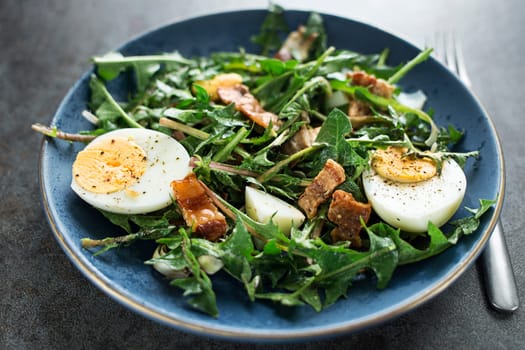 Dandelion salad with eggs and roasted bacon close up
