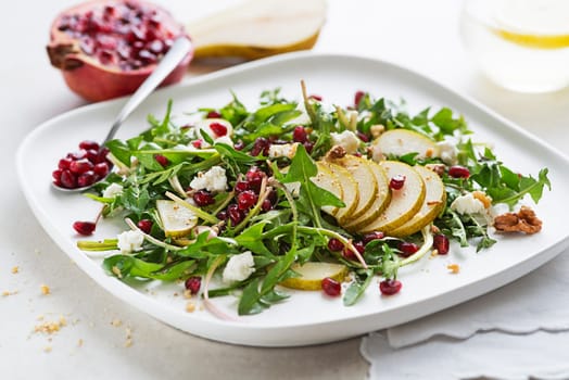 Healthy dandelion salad with pear fruit, pomegranate and fresh cheese close up