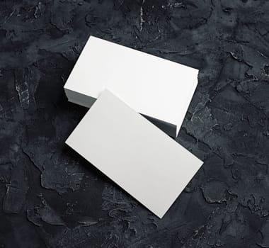 Blank white business cards on black plaster background. Mockup for branding identity. Blank template for design presentations and portfolios