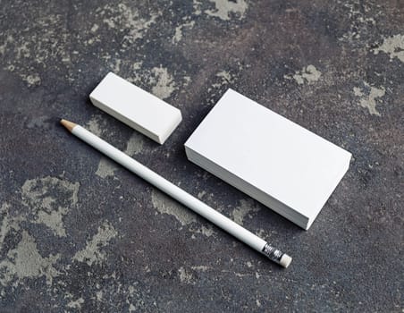 Blank business cards, pencil and eraser on concrete background. Stationery mockup. Objects for placing your design.