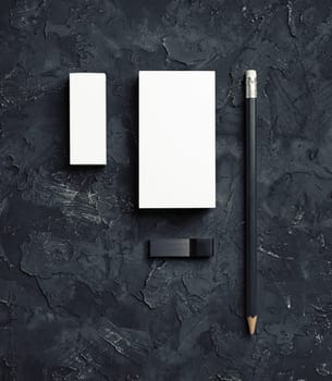 Blank business card, pencil, usb flash drive and eraser on black plaster background. Blank stationery set.