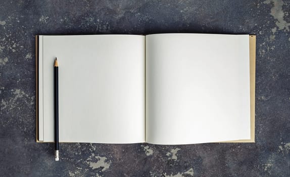 Blank book and pencil mock up on concrete background. Top view.