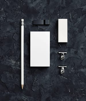 Corporate identity template on black plaster background. Blank business card, pencil, eraser, usb flash drive and metal clips. Top view.