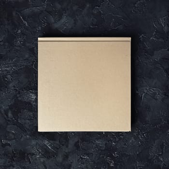 Closed blank square booklet on black plaster background. Top view.