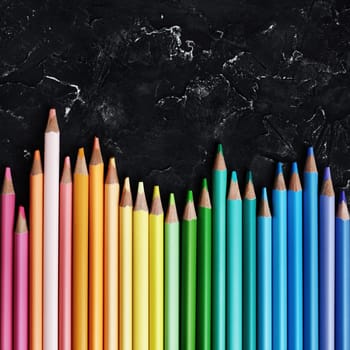 Color pencils on black plaster background. Beautiful color pencils. Top view.