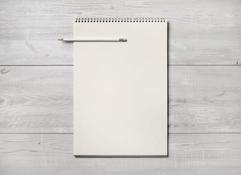 Photo of blank notepad and pencil on light wooden background. Responsive design template. Flat lay.