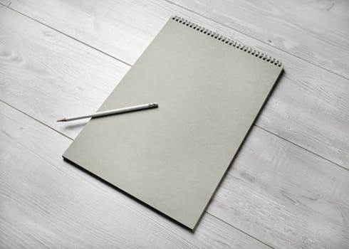 Photo of blank sketchbook and pencil on light wooden background. Responsive design template.