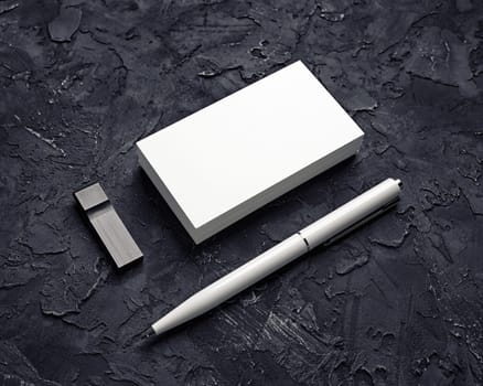 Blank business card, usb flash drive and pen on black plaster background. Mockup for branding identity. Template for graphic designers portfolios.